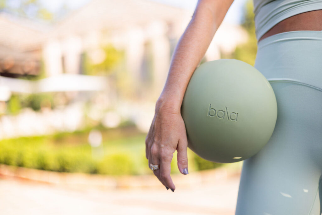 Woman holding a Bala Pilates ball during an outdoor True40 fitness workout